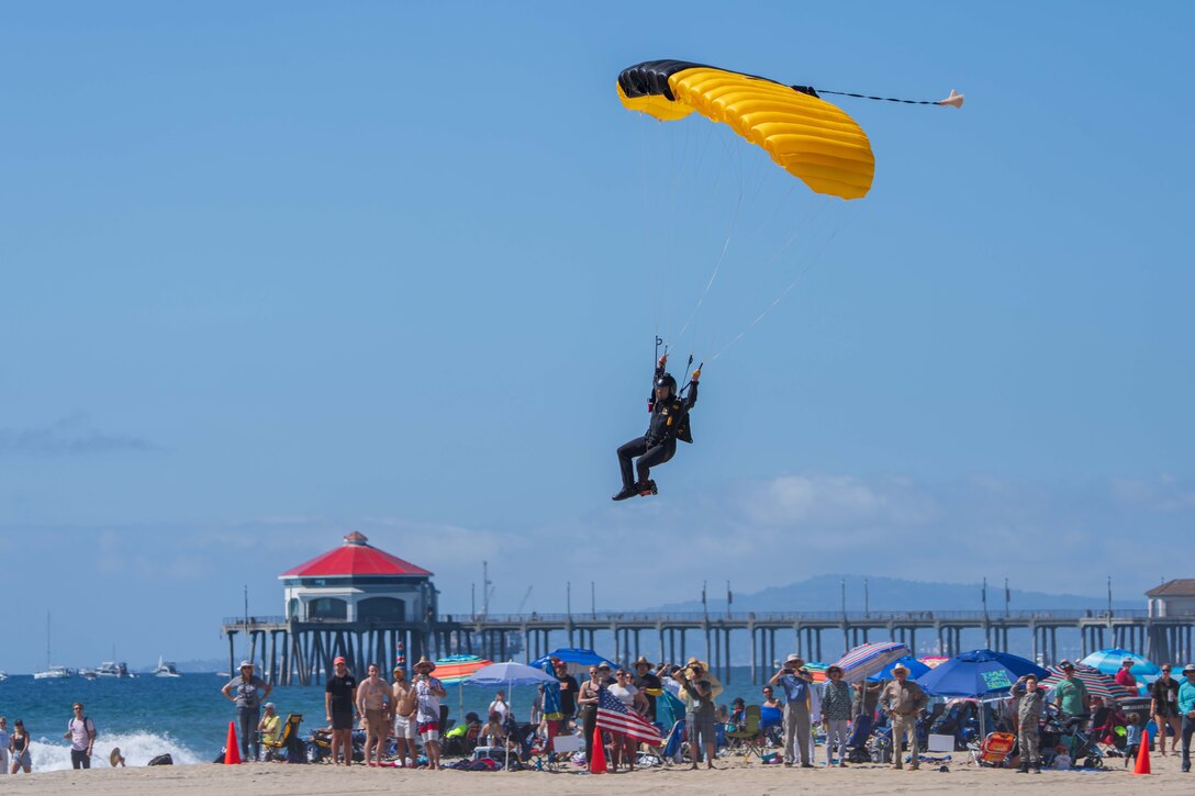 A man parachutes onto a crowded beach.