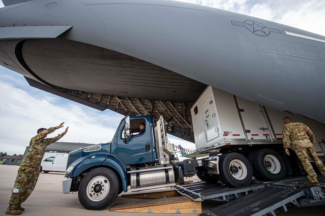 A large truck backs into the compartment of a plane.