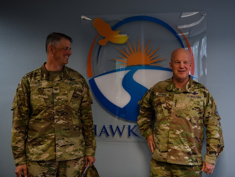 U.S. Space Force Gen. John W. “Jay” Raymond, right, and U.S. Space Force Col. Robert Long, Space Launch Delta 30 Commander, left, smile as they talk to a group during a visit to the Hawk’s Cove at Vandenberg Space Force Base, Calif., Oct. 11, 2022. Raymond visited the Hawk’s Cove for the first time since it was created, where it is first to combine all the military and civilian helping agencies, such as Equal Opportunity and the Sexual Assault Response coordinator’s office, into one centralized location. (U.S. Space Force photo by Airman 1st Class Ryan Quijas)