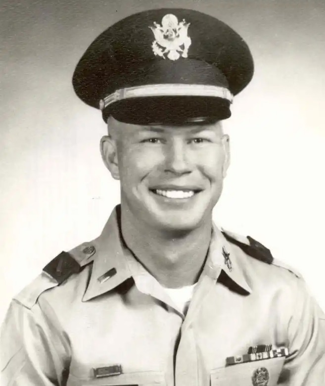 A man in cap and uniform smiles for a photo.