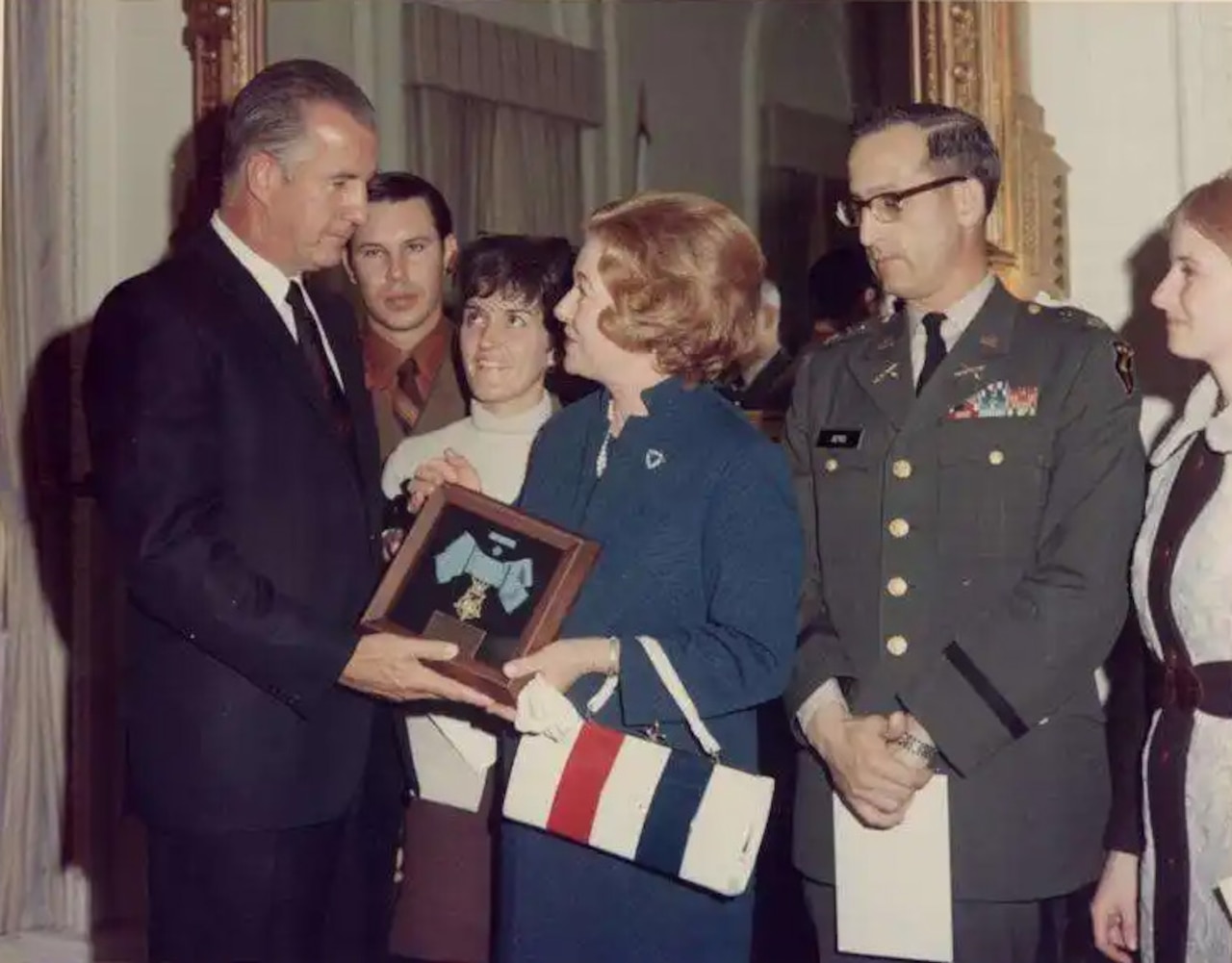 A man hands a woman a plaque while others stand behind them.