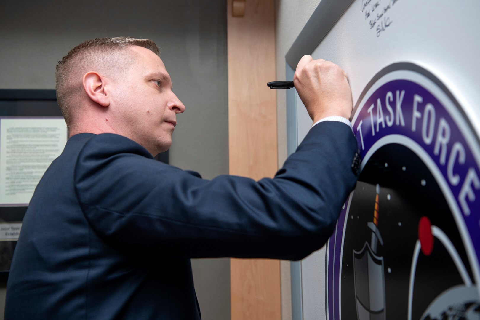 Man in suit signs board with marker