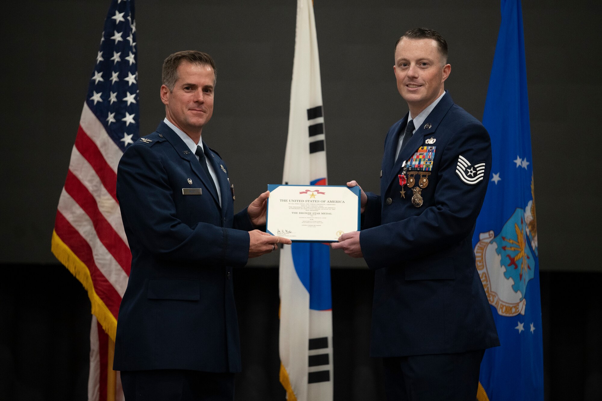 U.S. Air Force Col. Joshua Wood, 51st Fighter Wing Commander, presents U.S. Air Force Tech. Sgt. Jordan Locke, 51st Security Forces Squadron flight sergeant, the Bronze Star with Valor during a presentation ceremony at Osan Air Base, Republic of Korea, Oct. 12, 2022.