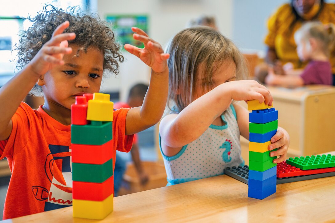 Two children build towers out of large Lego bricks.