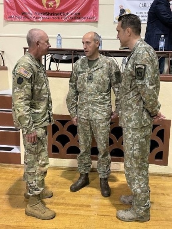 Pennsylvania Adjutant General Maj. Gen. Mark Schindler, left, talks with Brig. Gen. Arturas Radvilas, Lithuanian Land Forces commander, and Brig. Gen. Modestas Petrauskas, Lithuanian defense attaché to the United States and Canada, at the 28th Infantry Division departure ceremony in Harrisburg, Pa., on Oct. 9, 2022.