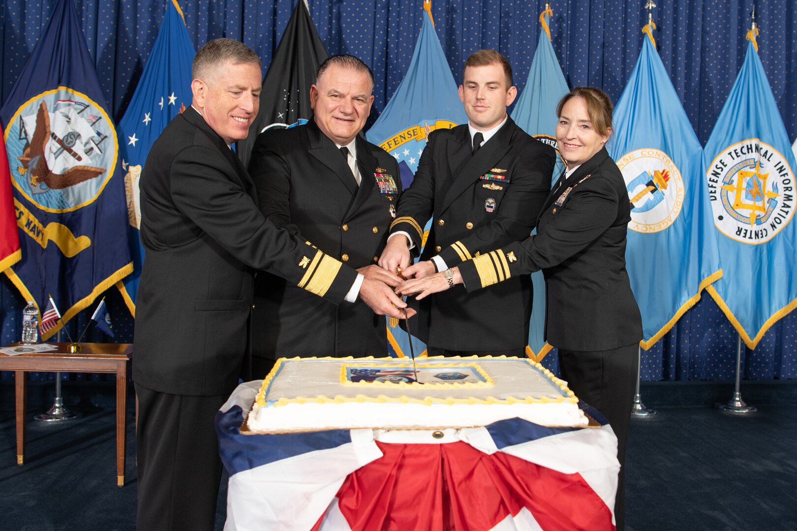 A group of sailors cut a Navy birthday cake.