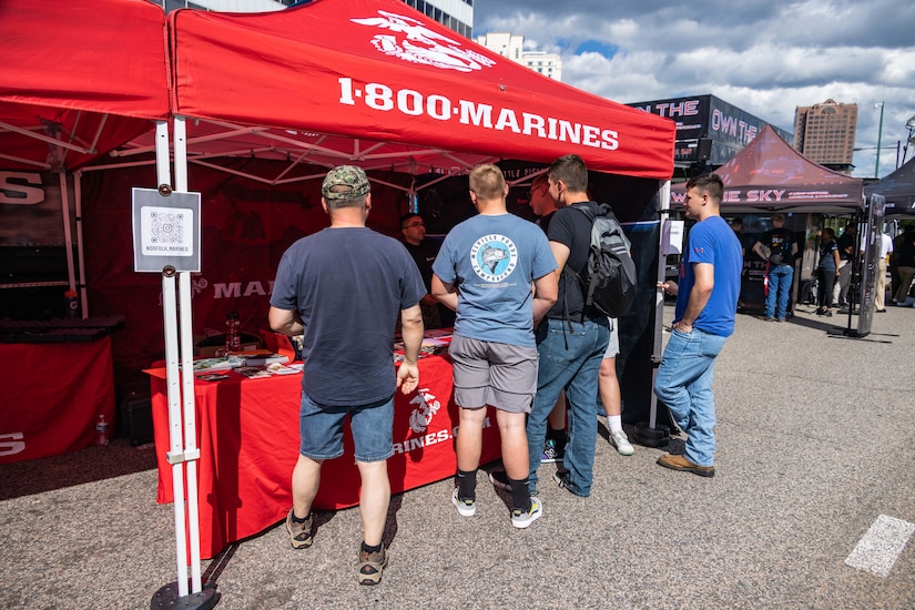 Civilians stand outdoors near a booth.