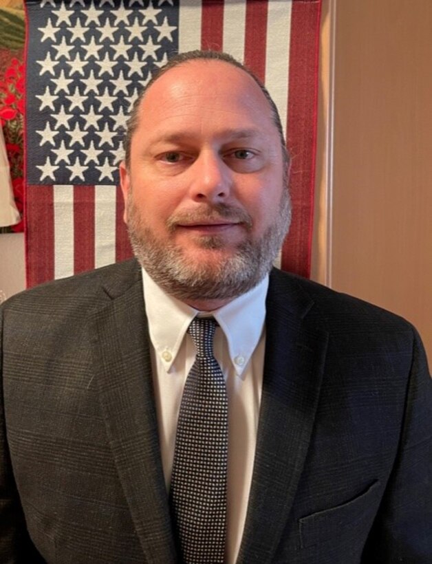 businessman poses in front of american flag