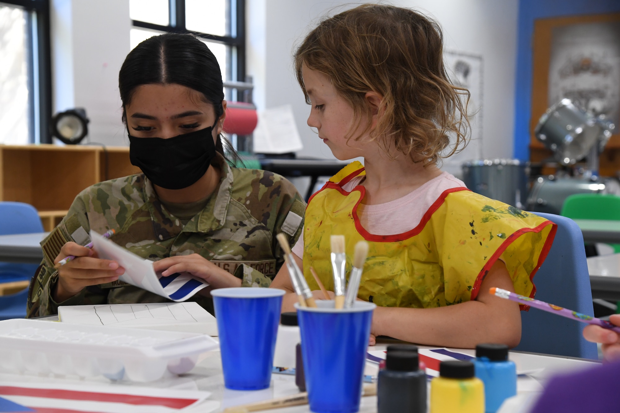 U.S. Air Force Airman 1st Class Mariah Vachon, 81st Force Support Squadron personnel technician, assists Alaina Zimmer, daughter of U.S. Navy Senior Chief Petty Officer Aviation Electronics Technician Robert Zimmer, Center for Naval Aviation Technical Training Unit Keesler instructor, with an art project inside the youth center at Keesler Air Force Base, Mississippi, Oct. 7, 2022. The event was held in celebration of Hispanic Heritage Month, which is celebrated Sept. 15 through Oct. 15.