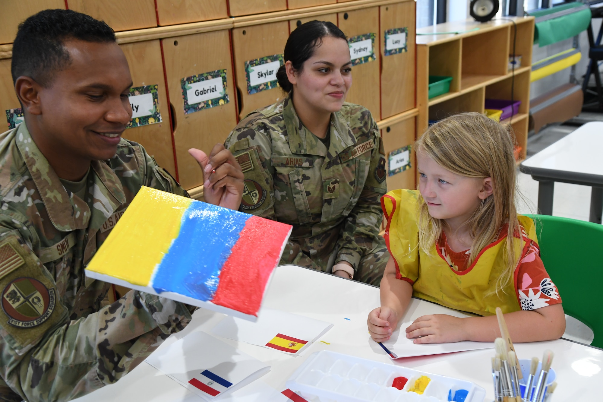 U.S. Air Force Airman 1st Class Leonard Smith, 81st Force Support Squadron retentions technician, assists Leah Cofer, daughter of Anna Russo, 81st FSS Fisher House administrative support clerk, with an art project as Staff Sgt. Rebekah Arias, 81st FSS manpower analyst, looks on inside the youth center at Keesler Air Force Base, Mississippi, Oct. 7, 2022. The event was held in celebration of Hispanic Heritage Month, which is celebrated Sept. 15 through Oct. 15.