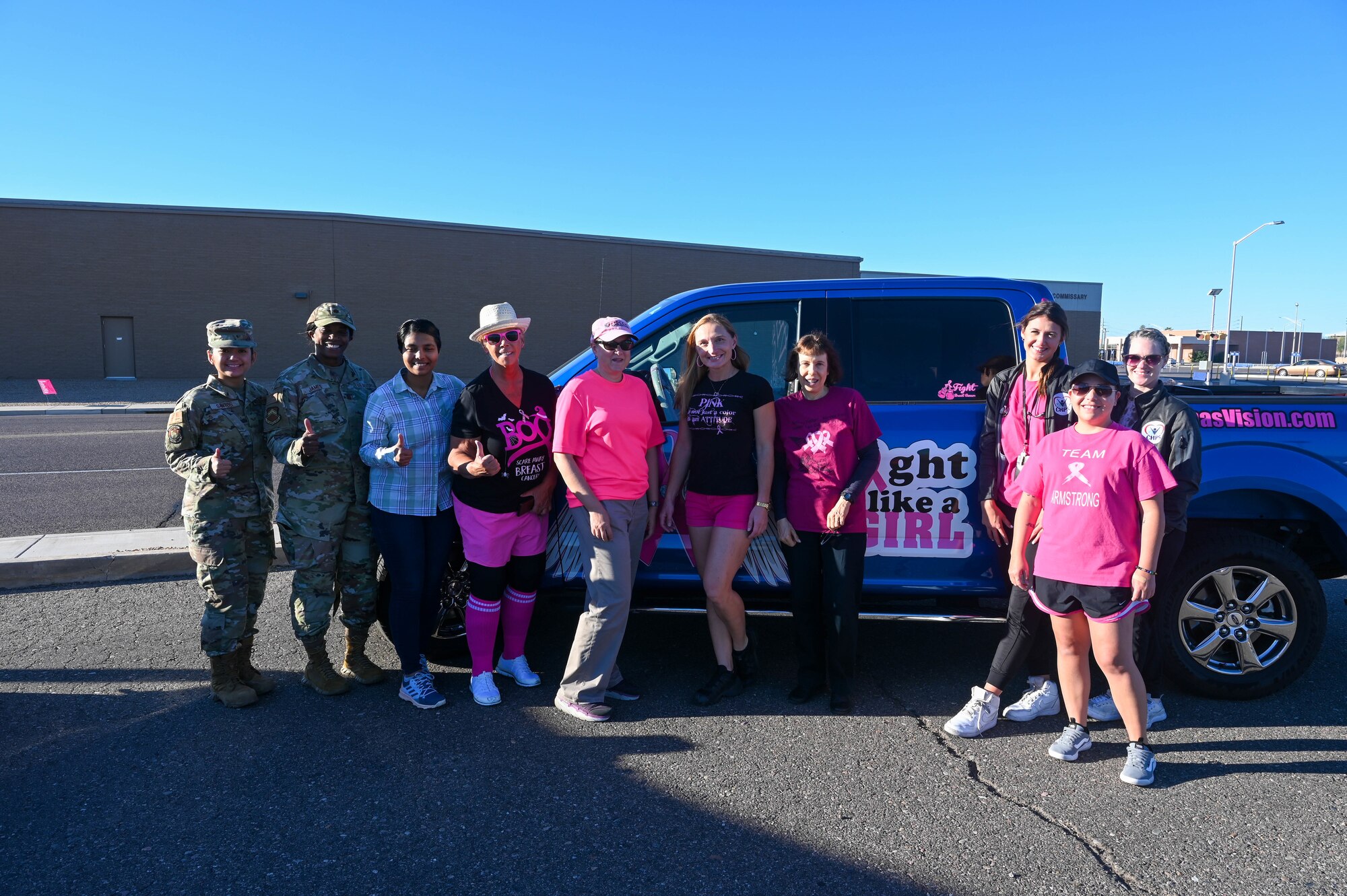 Members of the 56th Medical Group and the awareness organization Reba’s Vision pose in front of a promotional vehicle during a breast cancer awareness event Oct. 5, 2022, at Luke Air Force Base, Arizona.