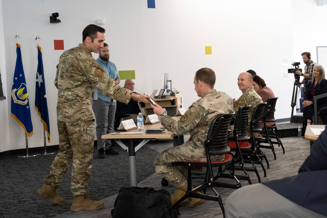 U.S. Air Force Tech. Sgt. Geoffrey Gilmer, a presenter from Air Force Test Center, demonstrates a test model universal remote to judges during the 2023 Spark Tank competition Oct. 6, 2022, at the Rapid Sustainment Office in Dayton, Ohio.