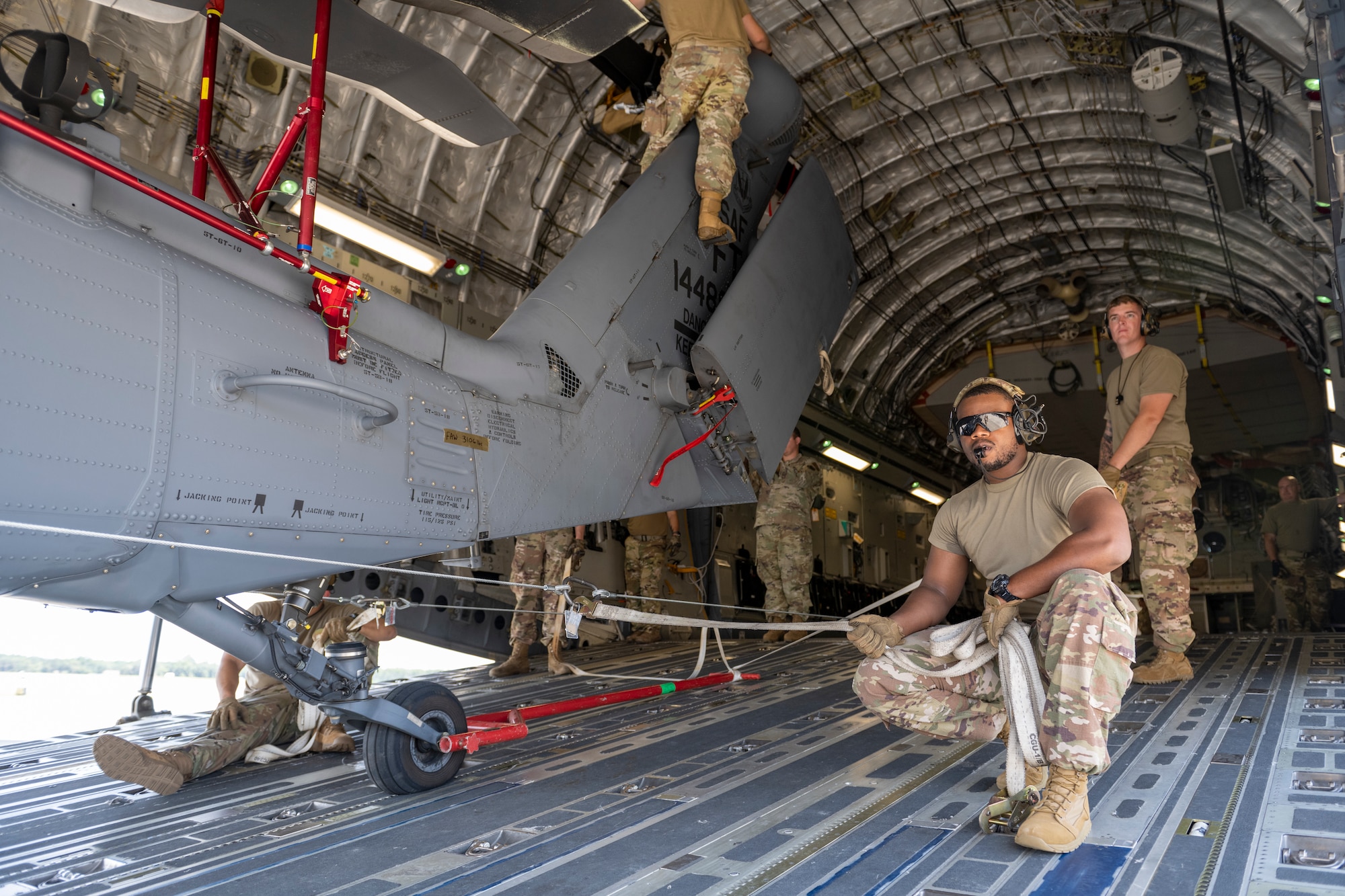 Airmen help load an HH-60W helicopter into a C-17 aircraft.