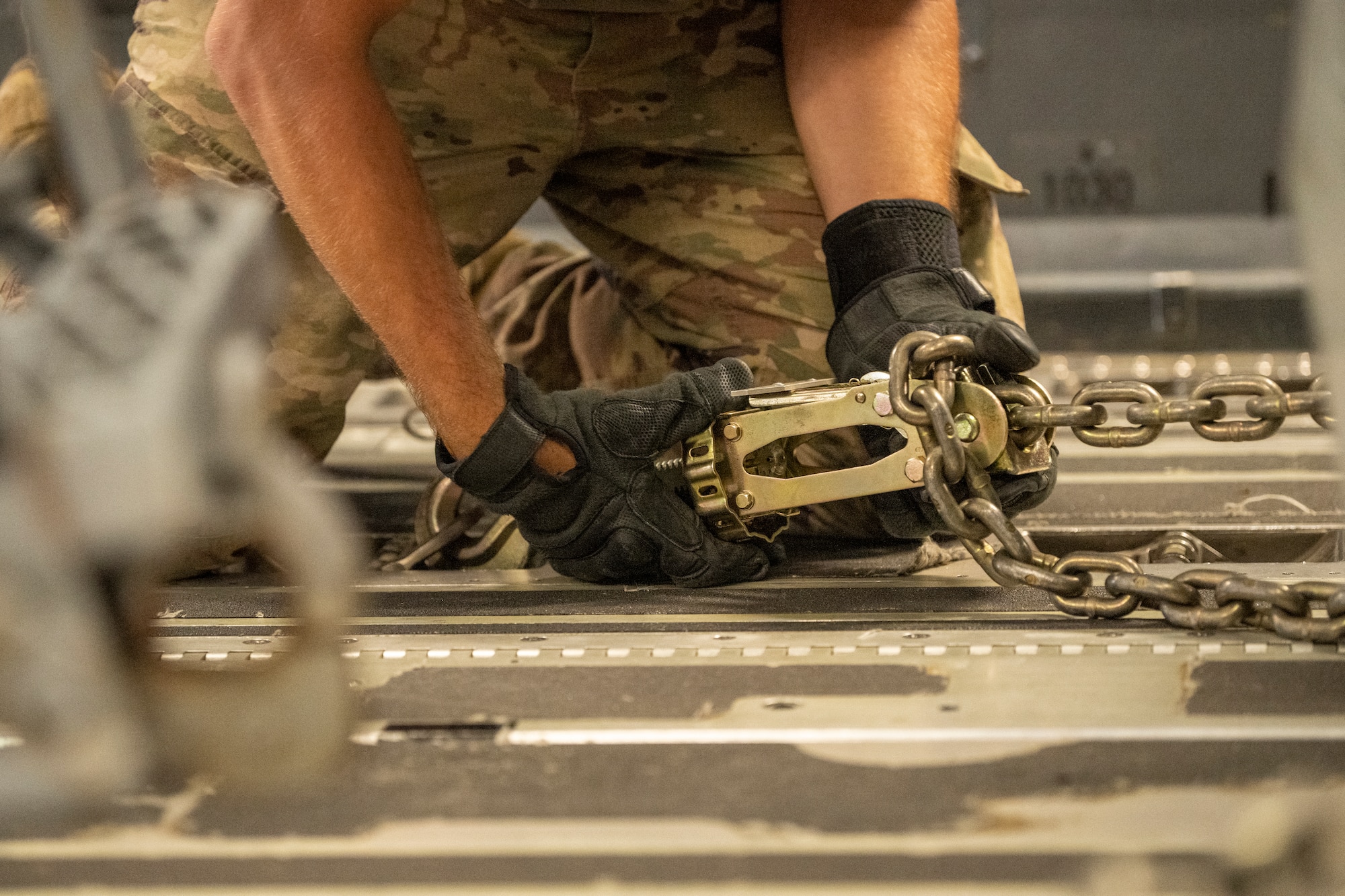 An Airman secures cargo to the floor of an aircraft