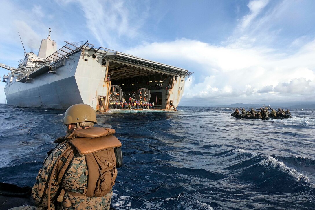 Marines in small rafts float toward a large ship.