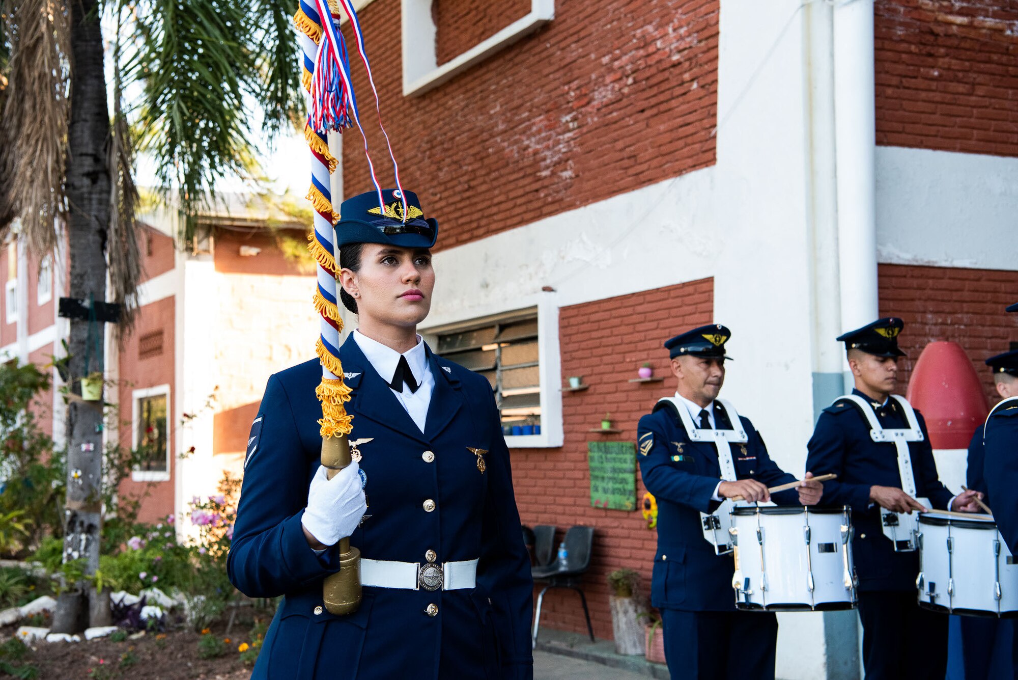 Woman in Paraguayan Air Force Band performs while standing next to two band members