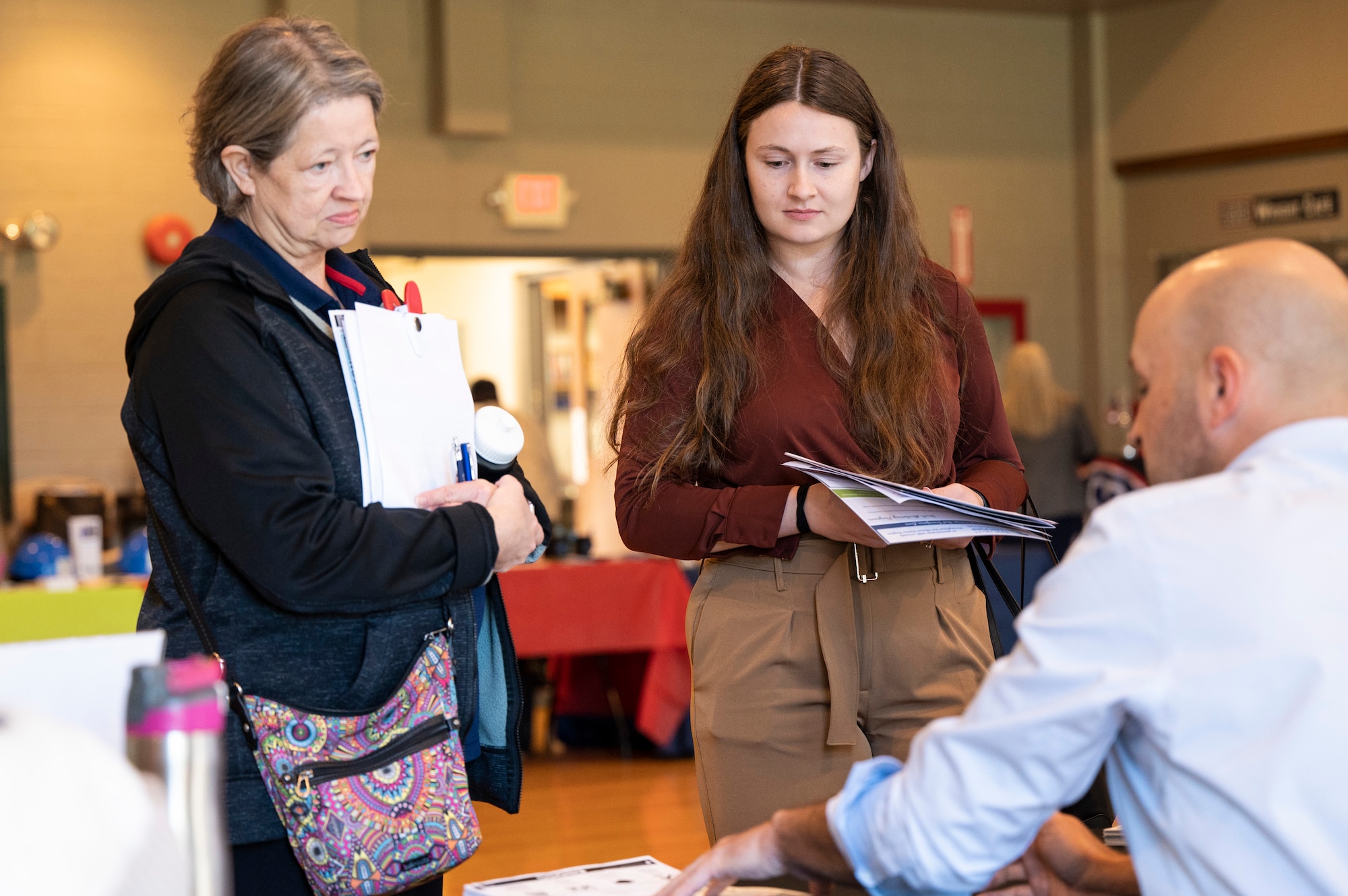 Two women speak to a booth attendee.