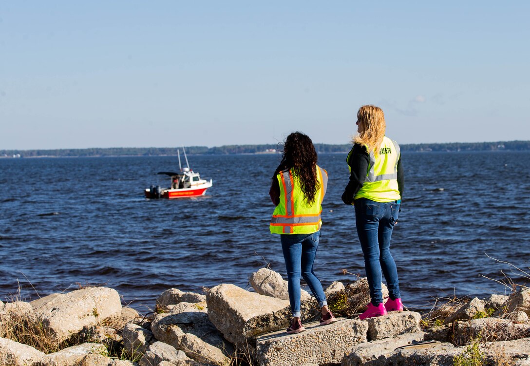 Cassandra Infante, left, and Valerie Miner, right, safety and standardization evaluators on Marine Corps Air Station (MCAS) Cherry Point, observe boats involved in the ongoing scenario from shore during the Sudden Crisis 2022 training exercise, MCAS Cherry Point, North Carolina, Oct. 11, 2022. The training event exercised command and control, reporting, interoperability with external organizations, and validated tactics, techniques and procedures, in the event the air station needs to elevate its force protection condition. (U.S. Marine Corps photo by Lance Cpl. Jade Farrington)