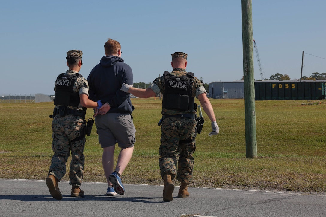 U.S. Marine Corps Cpl. Zubiate, left, and Lance Cpl. Closs, right, military police Marines, detain a role-player during the Sudden Crisis 2022 training exercise at Marine Corps Air Station Cherry Point, North Carolina, Oct. 11, 2022. The training event exercised command and control, reporting, interoperability with external organizations, and validated tactics, techniques and procedures, in the event the air station needs to elevate its force protection condition. (U.S. Marine Corps photo by Lance Cpl. Matthew Williams)