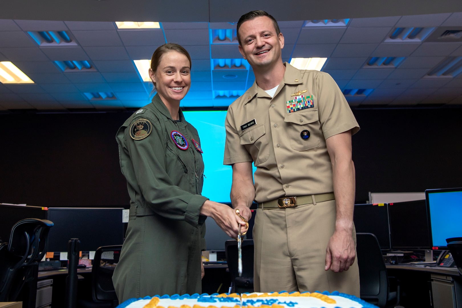Two Navy military personnel cut a birthday cake