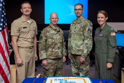 Group of military members posing for a group photo in front of a birthday cake