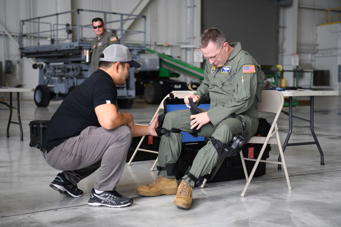 Brig. Gen. John Andrus, commander of 711th Human Performance Wing in the Air Force Research Laboratory, dons the pneumatically-powered exoskeleton with assistance from Dr. Linus Park with ROAM Robotics during an AFRL demonstration Oct. 6, 2022, at the 445th Airlift Wing, Wright-Patterson Air Force Base, Ohio.