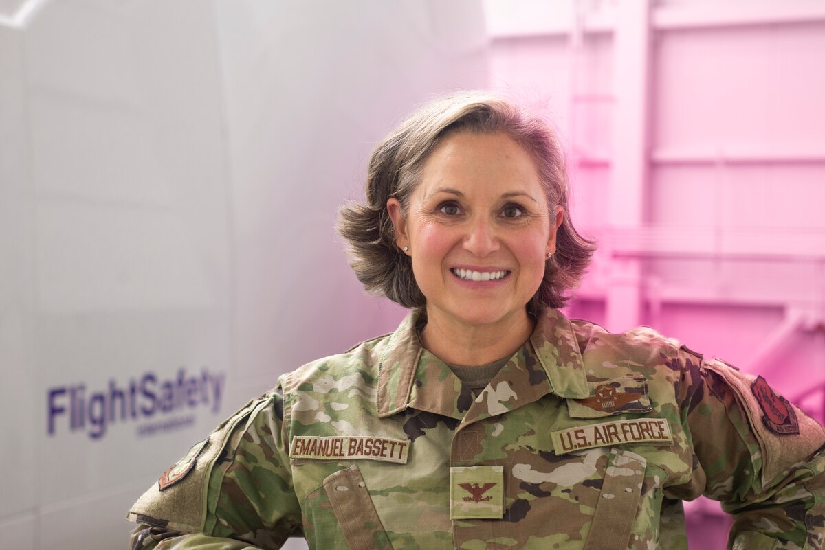 Col. Emanuel Bassett stands in front of a KC-46 flight simulator.