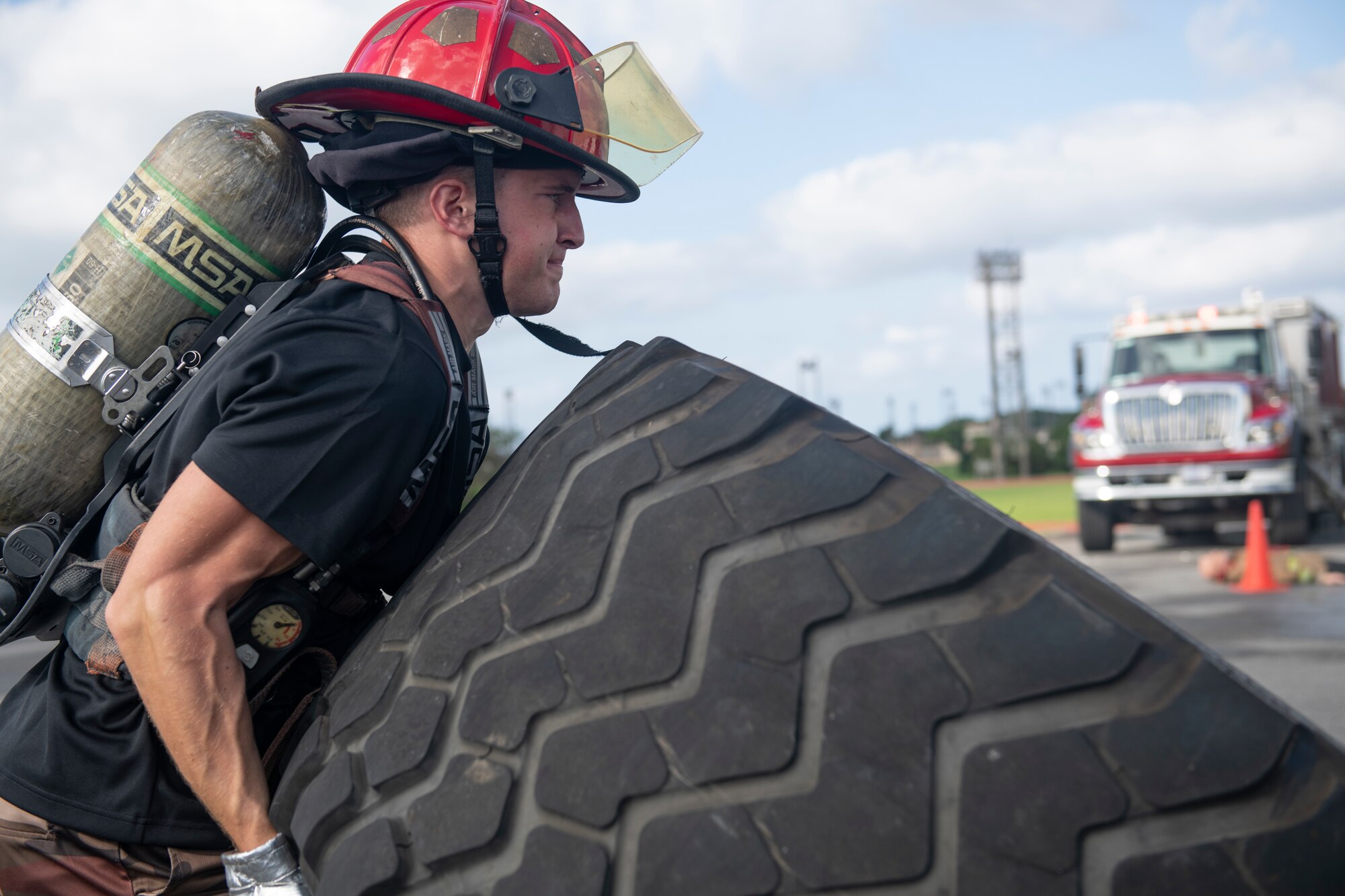 Airman 1st Class Aaron Smith, 718th Aircraft Maintenance Squadron crew chief, flips a tire at the fire muster challenge during National Fire Prevention Week at Kadena Air Base, Japan, Oct. 6, 2022. Fire Prevention Week is held annually to raise awareness on fire prevention measures and emergency procedures throughout the community. (U.S. Air Force photo by Senior Airman Jessi Roth)