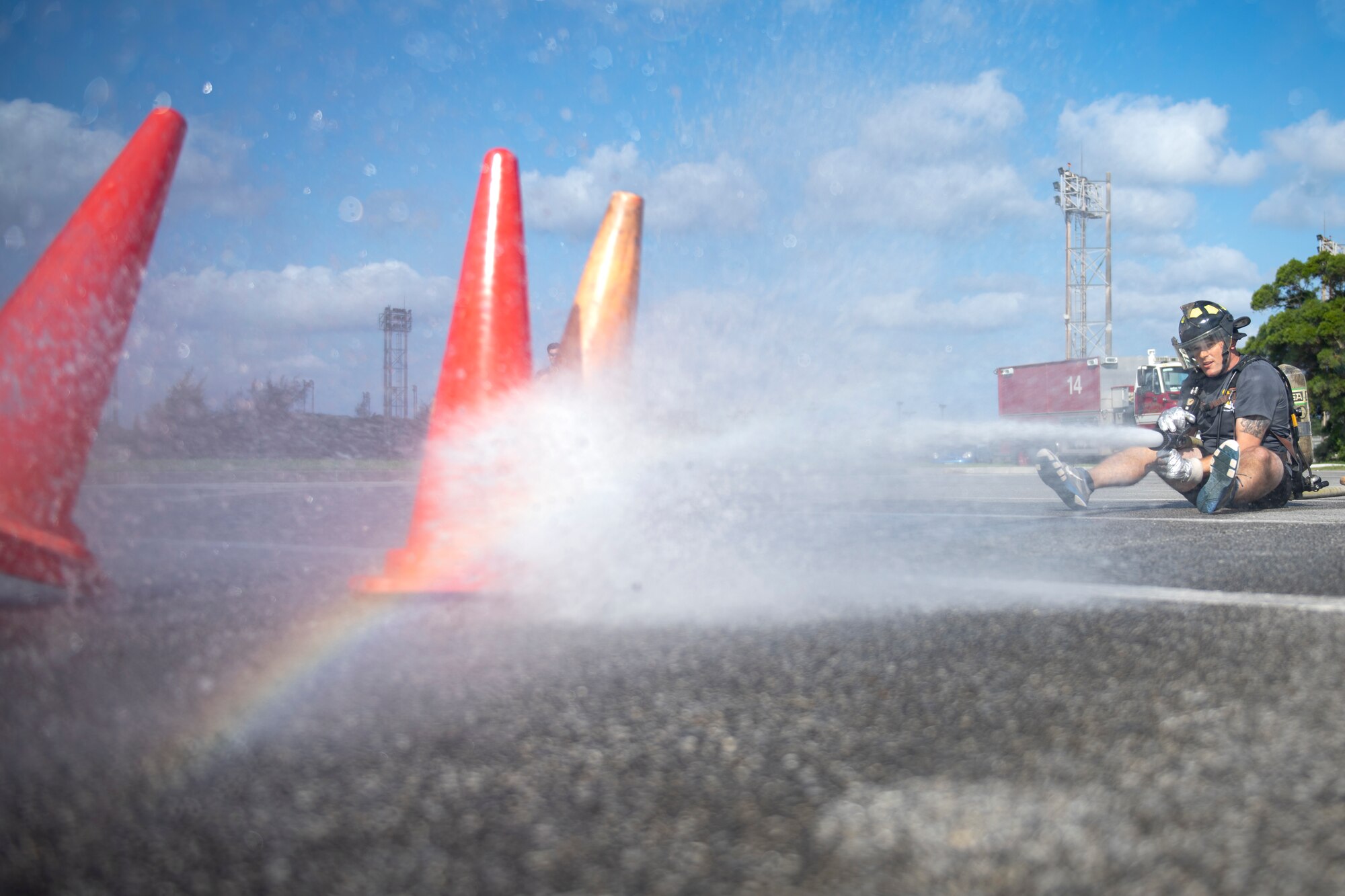 U.S. Air Force Capt. Drew Kerber, 18th Civil Engineer Squadron group executive officer, displaces traffic cones with a fire hose at the fire muster challenge during National Fire Prevention Week at Kadena Air Base, Japan, Oct. 6, 2022. The relay event gave teams of four the opportunity to compete for best time while conquering firefighter training-related obstacles. (U.S. Air Force photo by Senior Airman Jessi Roth)