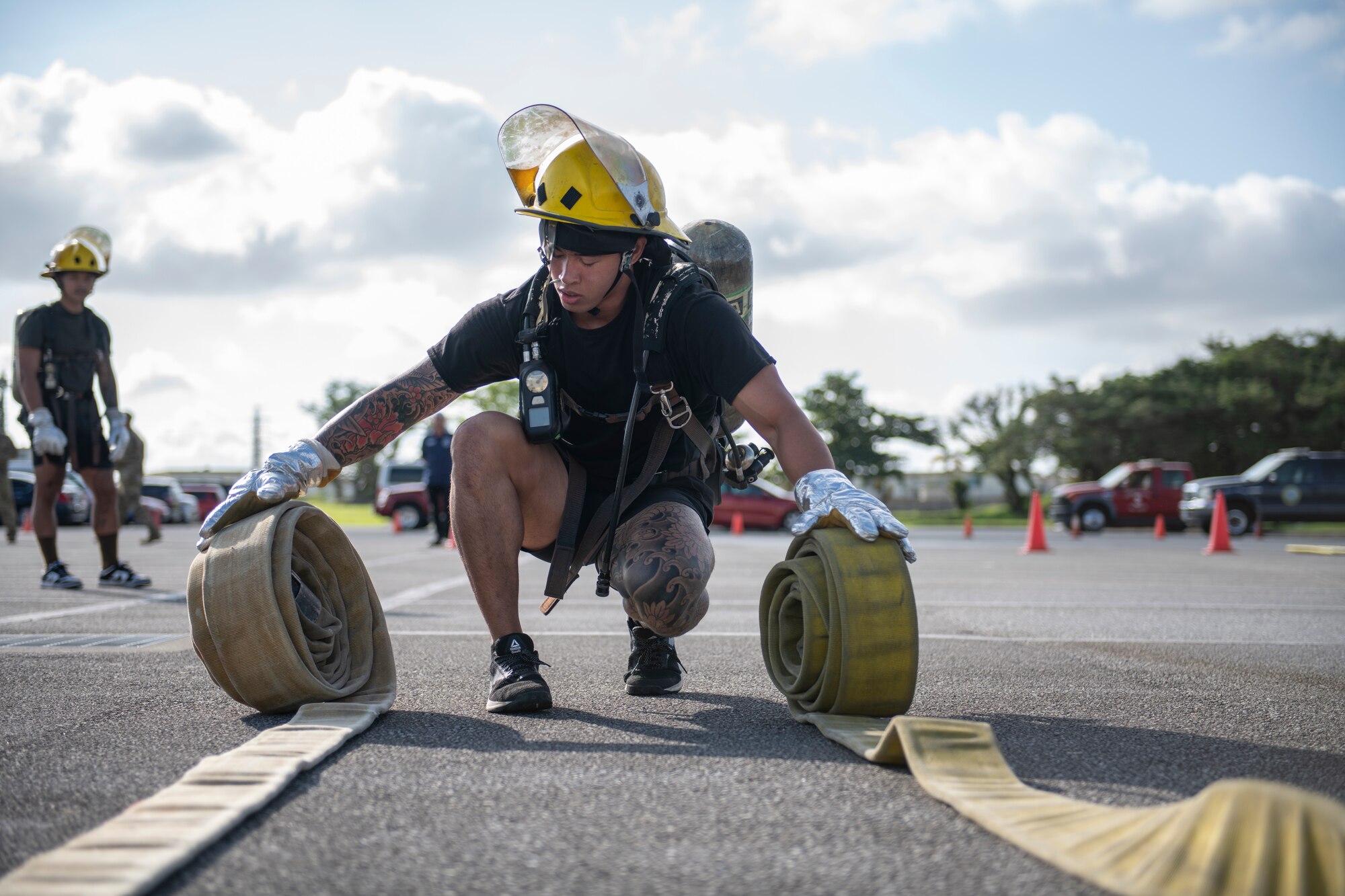 A U.S. Air Force Airman rolls hoses at the fire muster challenge during National Fire Prevention Week at Kadena Air Base, Japan, Oct. 6, 2022. The competition gave bystanders and participants an opportunity to see and experience the various types of physical exertion firefighters must prepare for when responding to emergencies. (U.S. Air Force photo by Senior Airman Jessi Roth)