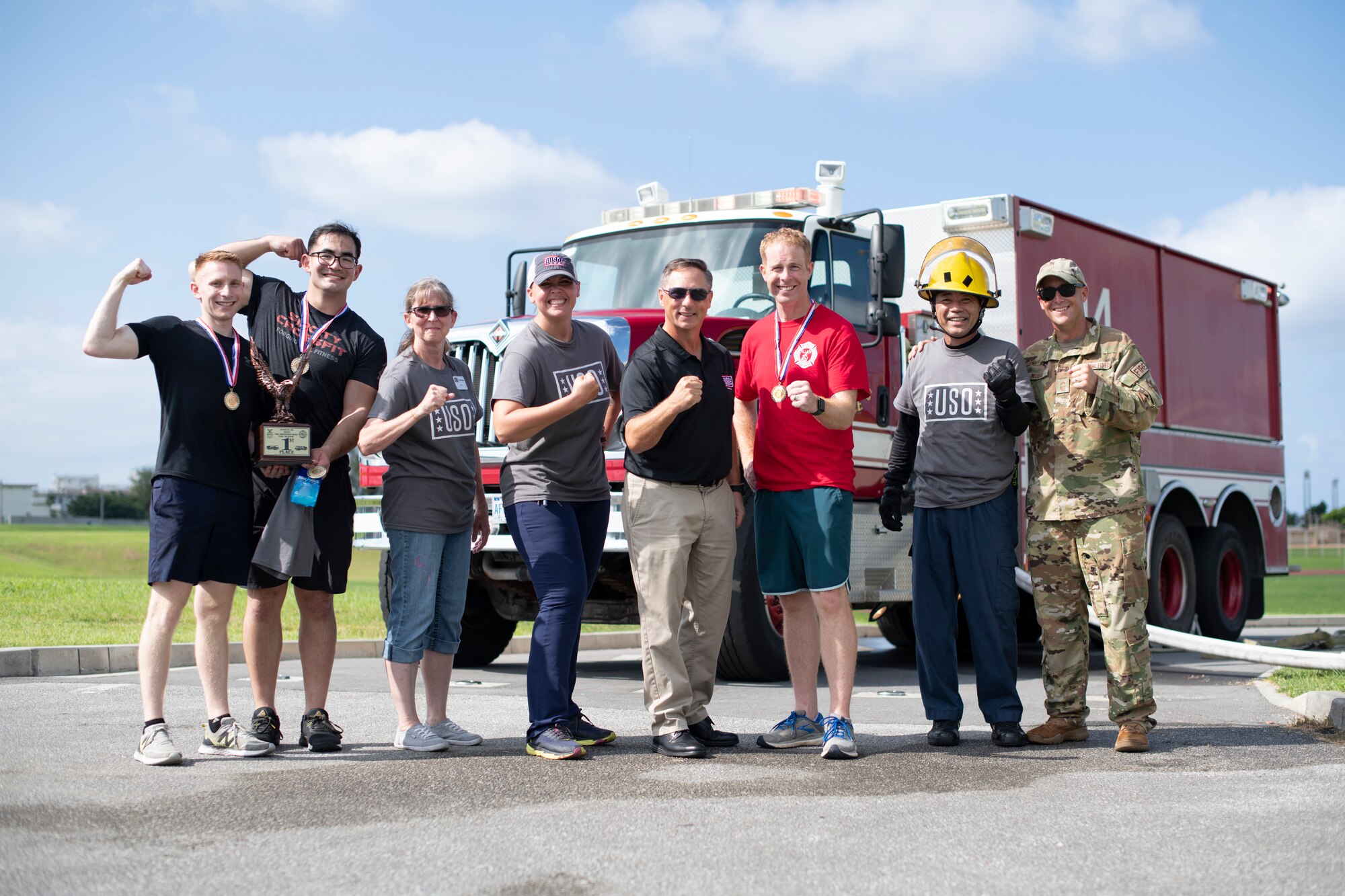 Airmen from the fire muster challenge winning team pose for a photo with members of the USO staff at Kadena Air Base, Japan, Oct. 6, 2022. The winning team finished the challenge with a top time of 4 minutes and 2 seconds, beating their closest competition by more than thirty seconds. (U.S. Air Force photo by Senior Airman Jessi Roth)
