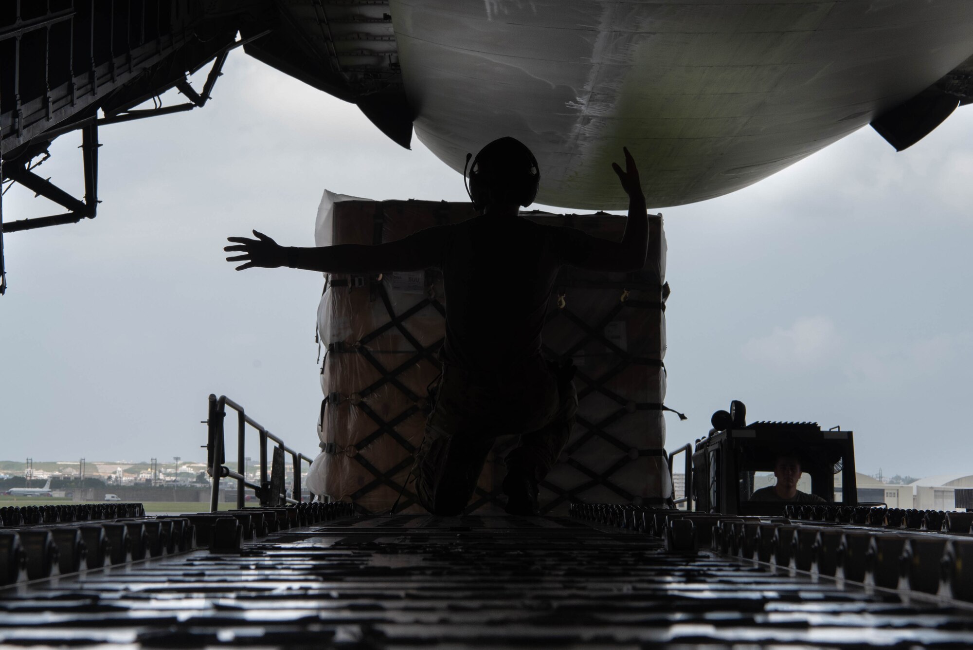 An Airman gives signals to a load vehicle.