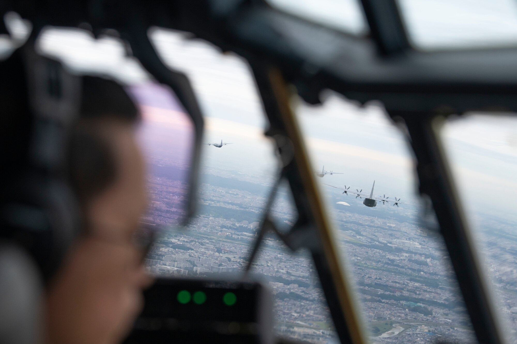 A Pilot looks out of a window while flying in a formation