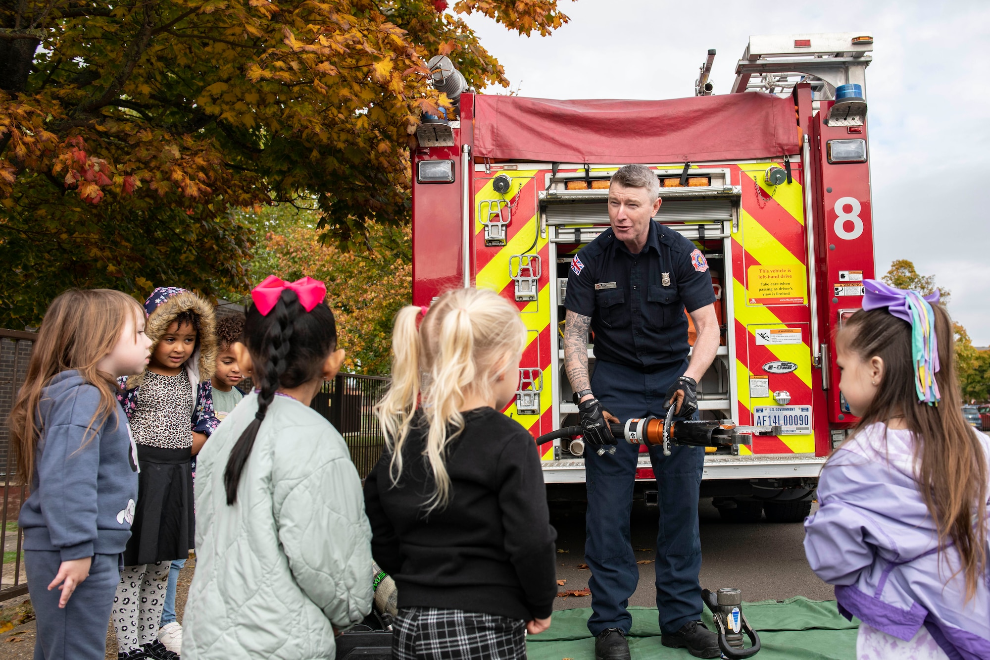 Stephen Poore, 423d Civil Engineer Squadron firefighter, shows RAF Alconbury Elementary School students the equipment that firefighters use, at RAF Alconbury, England, Oct. 13, 2022. This demonstration was a part of Fire Prevention Week and in which firefighters from the 423d CES educated Airmen and family members on proper fire safety habits. (U.S. Air Force photo by Senior Airman Jason W. Cochran)