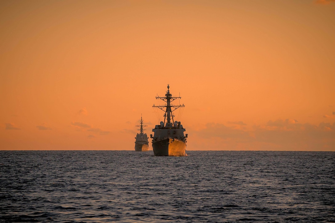 Two  ships move through the water.