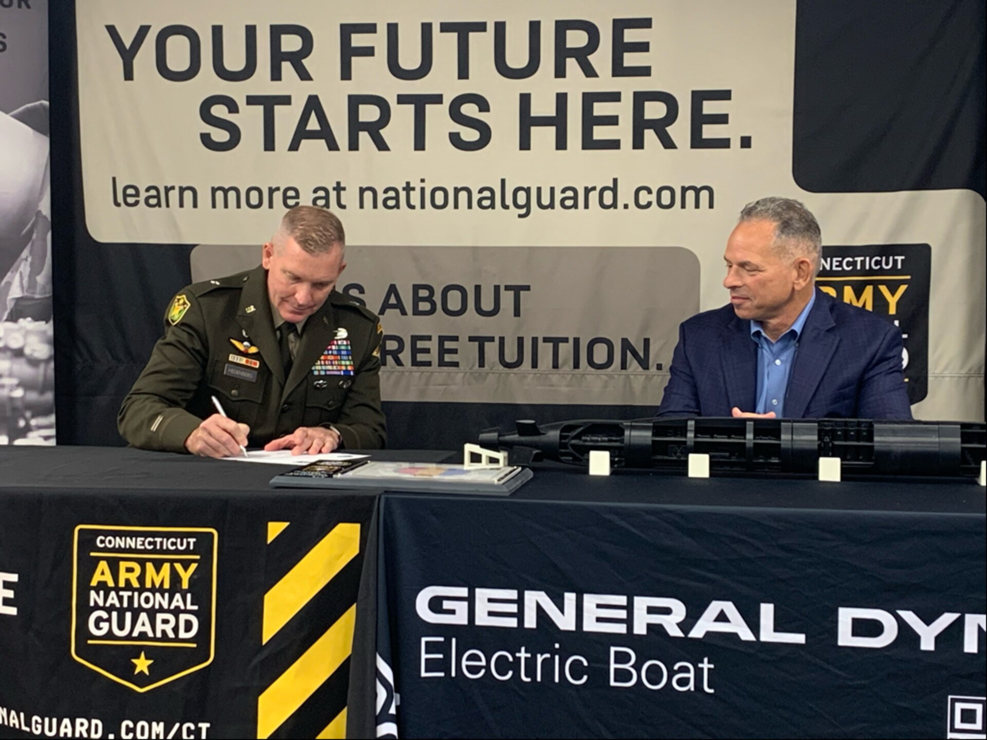 Two men sign a document
