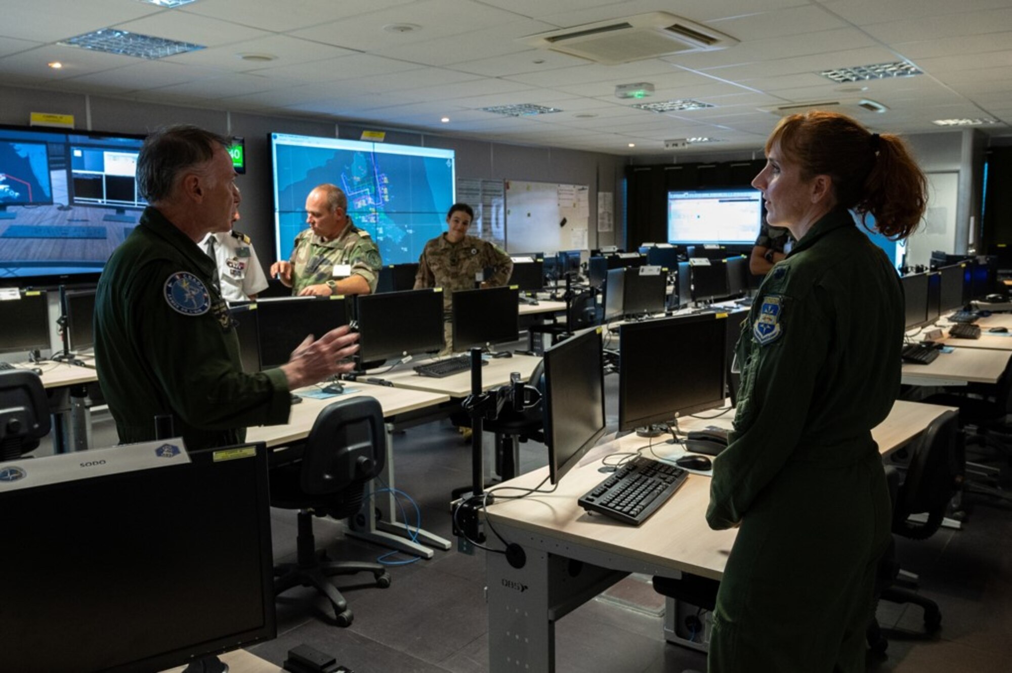 photo of  French air force member briefing a  US military member in a room full for computers