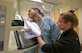 Mammography technician performs simulated mammogram on female Airman.