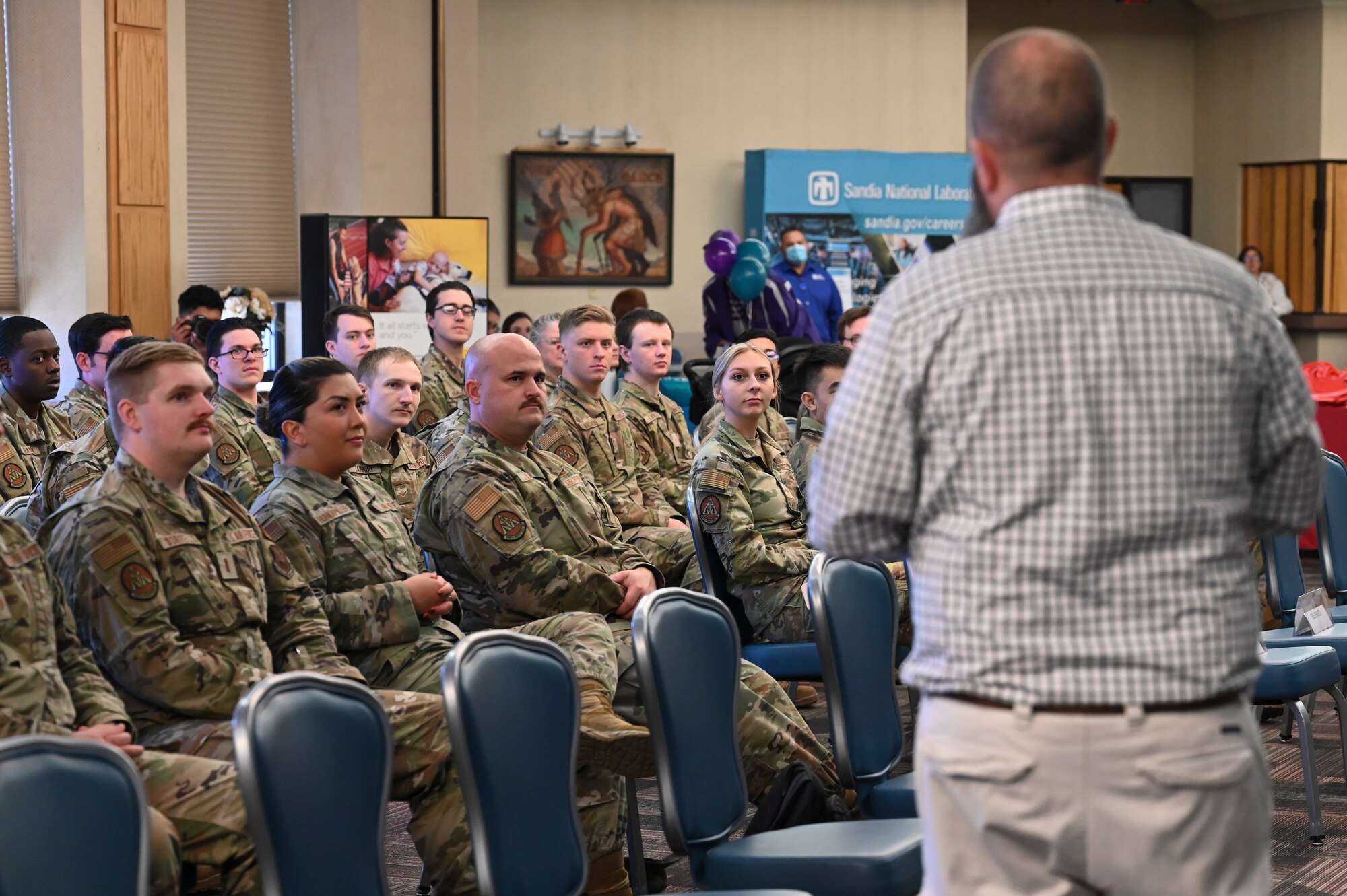 A group of people listen to a man speak.