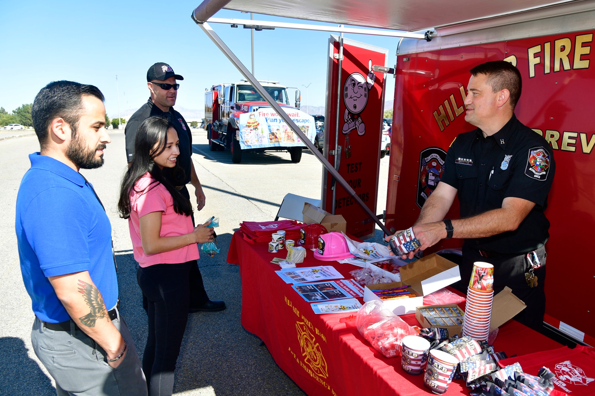 (At left) Chris Espinoza, F-16 System Program Office, and his wife Lora visit with Bryan Griffiths, 775th Civil Engineer Squadron fire Inspector, at a display booth in the Exchange parking lot Oct. 13, 2022, at Hill Air Force Base, Utah. In celebration of Fire Prevention Week, Hill Fire and Emergency Services held outreach events during the week to educate and raise awareness about fire dangers and prevention. (U.S. Air Force photo by Todd Cromar)