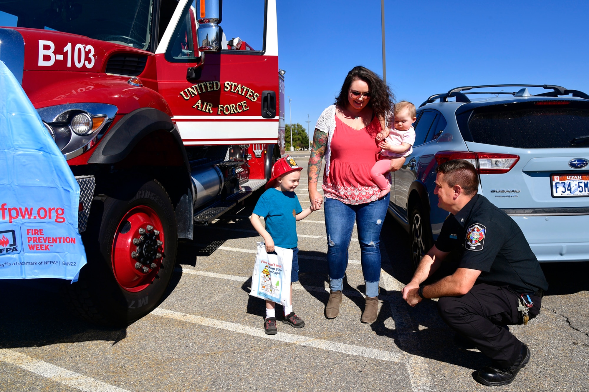 (At left) Casandra Kruskie, her son Jacob and daughter Olivia visit with Bryan Griffiths, 775th Civil Engineer Squadron fire Inspector, near a fire truck display in the Exchange parking lot Oct. 13, 2022, at Hill Air Force Base, Utah. In celebration of Fire Prevention Week, Hill Fire and Emergency Services held outreach events during the week to educate and raise awareness about fire dangers and prevention. (U.S. Air Force photo by Todd Cromar)