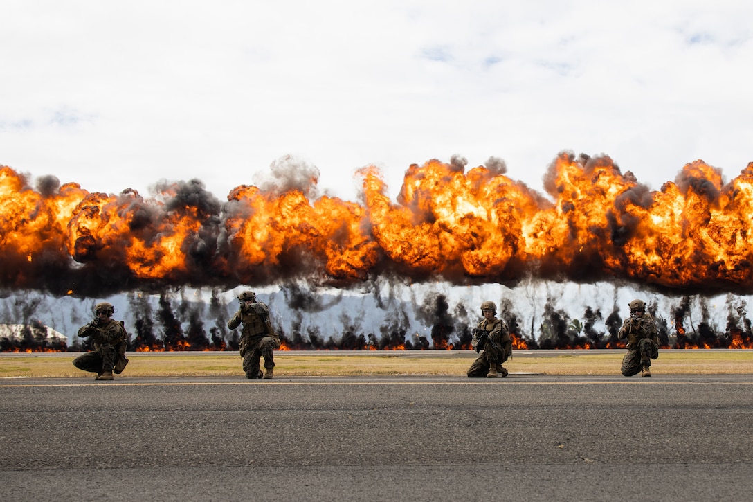 U.S. Marines with 3d Littoral Combat Team, 3rd Marine Littoral Regiment, take a knee in front of an explosives display, nicknamed the "Wall of Fire," during a Joint Air-Ground Task Force Demonstration as part of the 2022 Kaneohe Bay Air Show, Marine Corps Air Station Kaneohe Bay, Marine Corps Base Hawaii, Aug. 13, 2022. The air show provided an opportunity to showcase the aircraft, equipment and capabilities of the armed forces to the local community. The Kaneohe Bay Air Show, which contained aerial performances, static displays, demonstrations and vendors, was designed to celebrate MCBH’s longstanding relationship with the local community. (U.S. Marine Corps photo by Cpl. Brandon Aultman)