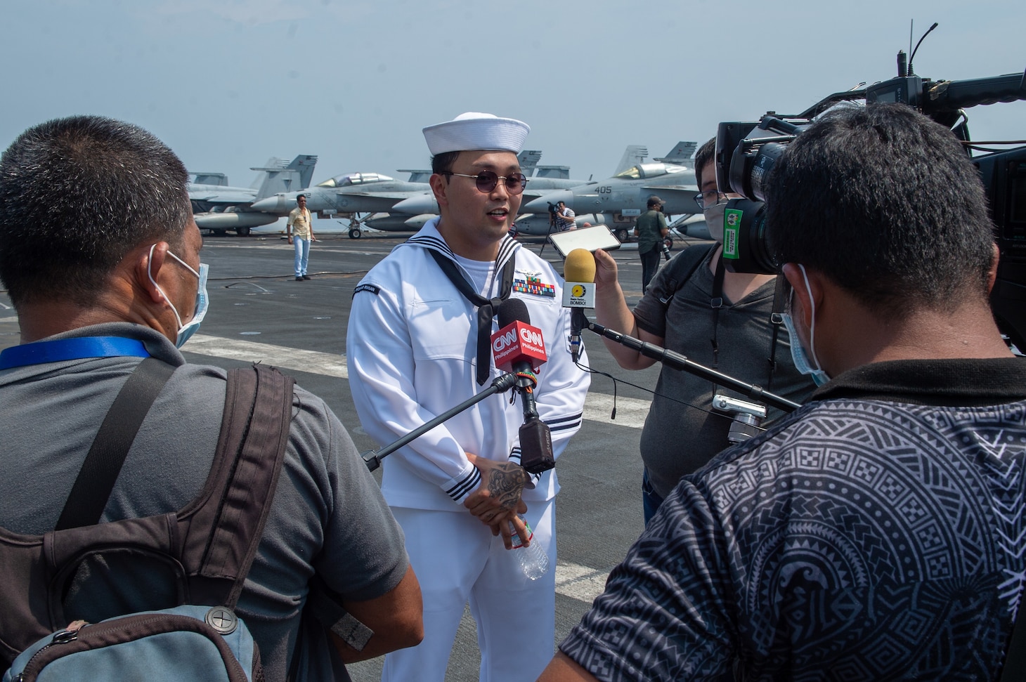 221014-N-IG750-1082 MANILA BAY (Oct. 14, 2022) Personnel Specialist Second Class Brandon Romero, from Jacksonville, Florida, answers interview questions from local media outlets on the flight deck of the U.S. Navy’s only forward-deployed aircraft carrier, USS Ronald Reagan (CVN 76), while at anchor in Manila Bay, Philippines, Oct. 14. Ronald Reagan, the flagship of Carrier Strike Group 5 provides a combat-ready force that protects and defends the United States, and supports alliances, partnerships and collective maritime interests in the Indo-Pacific region. (U.S. Navy photo by Mass Communication Specialist 2nd Class Caleb Dyal)