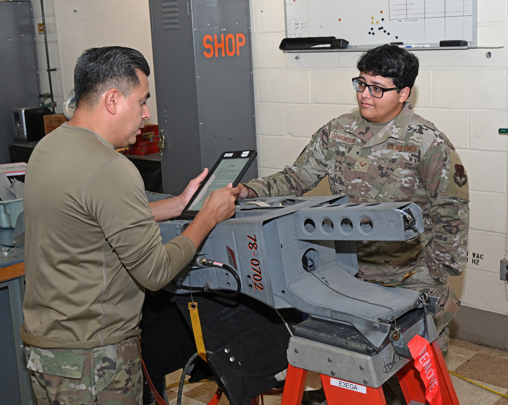 U.S. Air Force Staff Sgt. Alfredo Lepe (left), a 7-level egress systems technician assigned to the 175th Maintenance Squadron, reads over a technical order while training U.S. Air Force Senior Airman Natalia Cuevas Mercado, an egress systems technician with the 175th Maintenance Squadron, at Warfield Air National Guard Base at Martin State Airport in Middle River, Maryland, October 6, 2022.