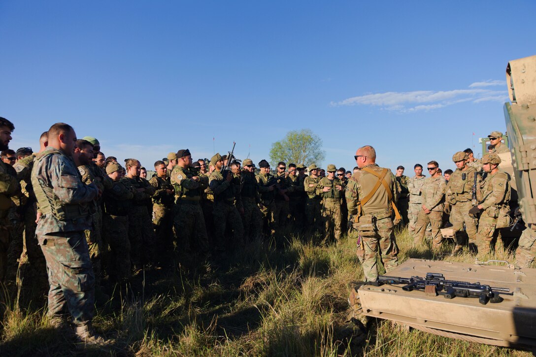 A U.S. service member stands in front of a group of Portuguese service members.