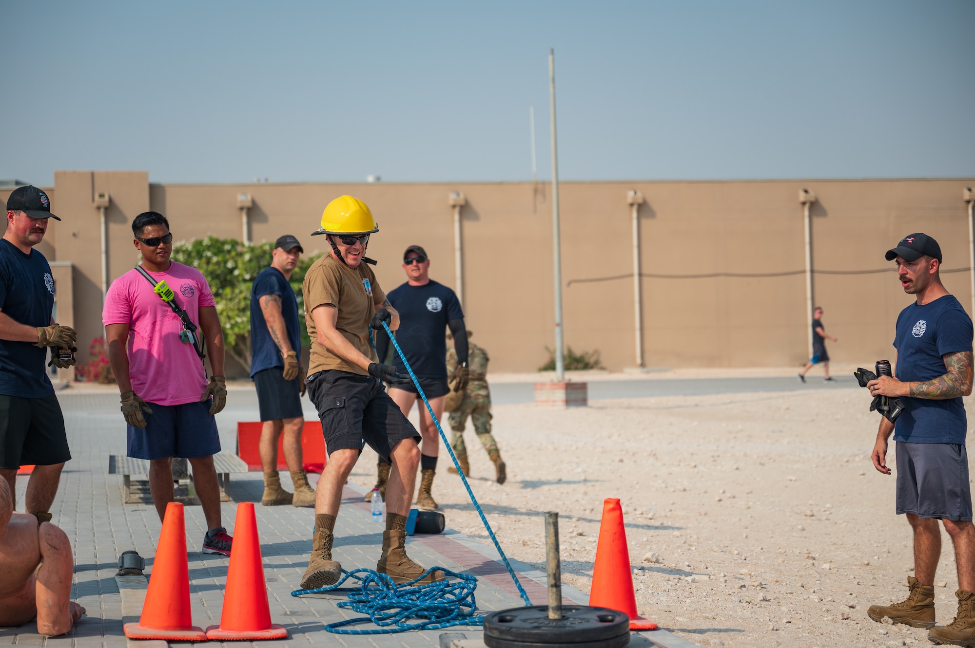 U.S. Air Force firefighters assigned to the 379th Expeditionary Civil Engineering Squadron drag a weighted sled while competing in the fire rodeo exercise Oct 15, 2022 at Al Udeid Air Base, Qatar. During fire safety week the firefighters conducted the fire rodeo where they hosted an open competition featuring elements of physical prowess needed to perform the lifesaving skills associated with their job. (U.S. Air Force photo by Staff Sgt. Dana Tourtellotte)