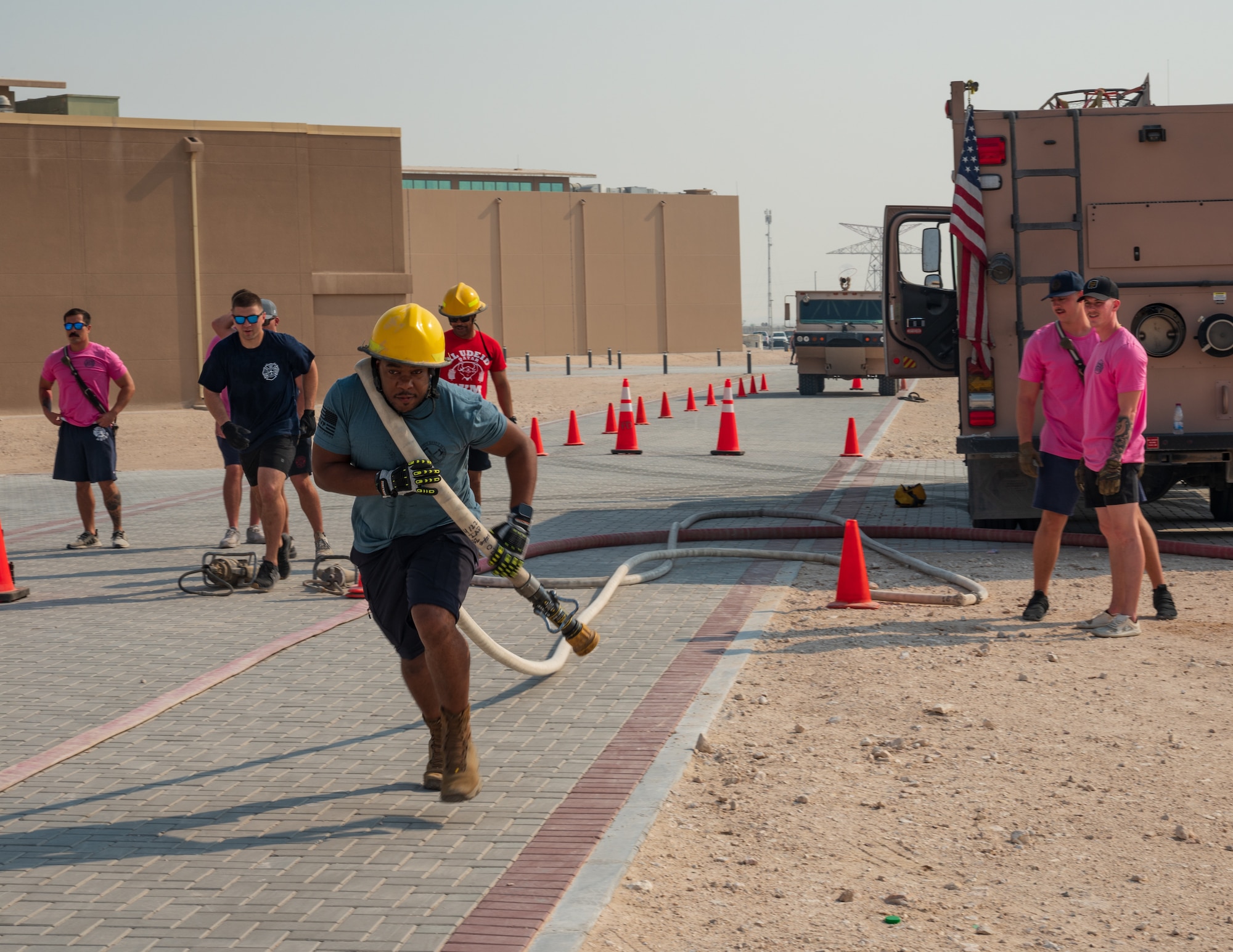 .S. Air Force firefighters assigned to the 379th Expeditionary Civil Engineering Squadron run with a fire hose while competing in the fire rodeo exercise Oct 15, 2022 at Al Udeid Air Base, Qatar. During fire safety week the firefighters conducted the fire rodeo where they hosted an open competition featuring elements of physical prowess needed to perform the lifesaving skills associated with their job. (U.S. Air Force photo by Staff Sgt. Dana Tourtellotte)