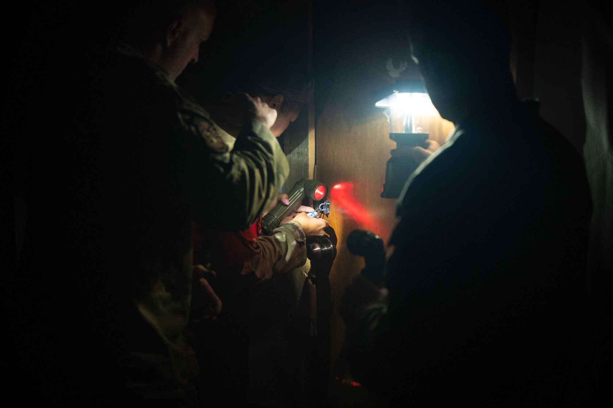 U.S. Air Force Airmen work together to unlock a padlocked door during a fire escape room exercise as part of fire safety awareness week Oct. 12, 2022 at Al Udeid Air Base, Qatar. These Airmen had to work together to find clues, unlock padlocks and perform a rescue as part of an exercise to impress upon people the importance and challenge of fire safety awareness.