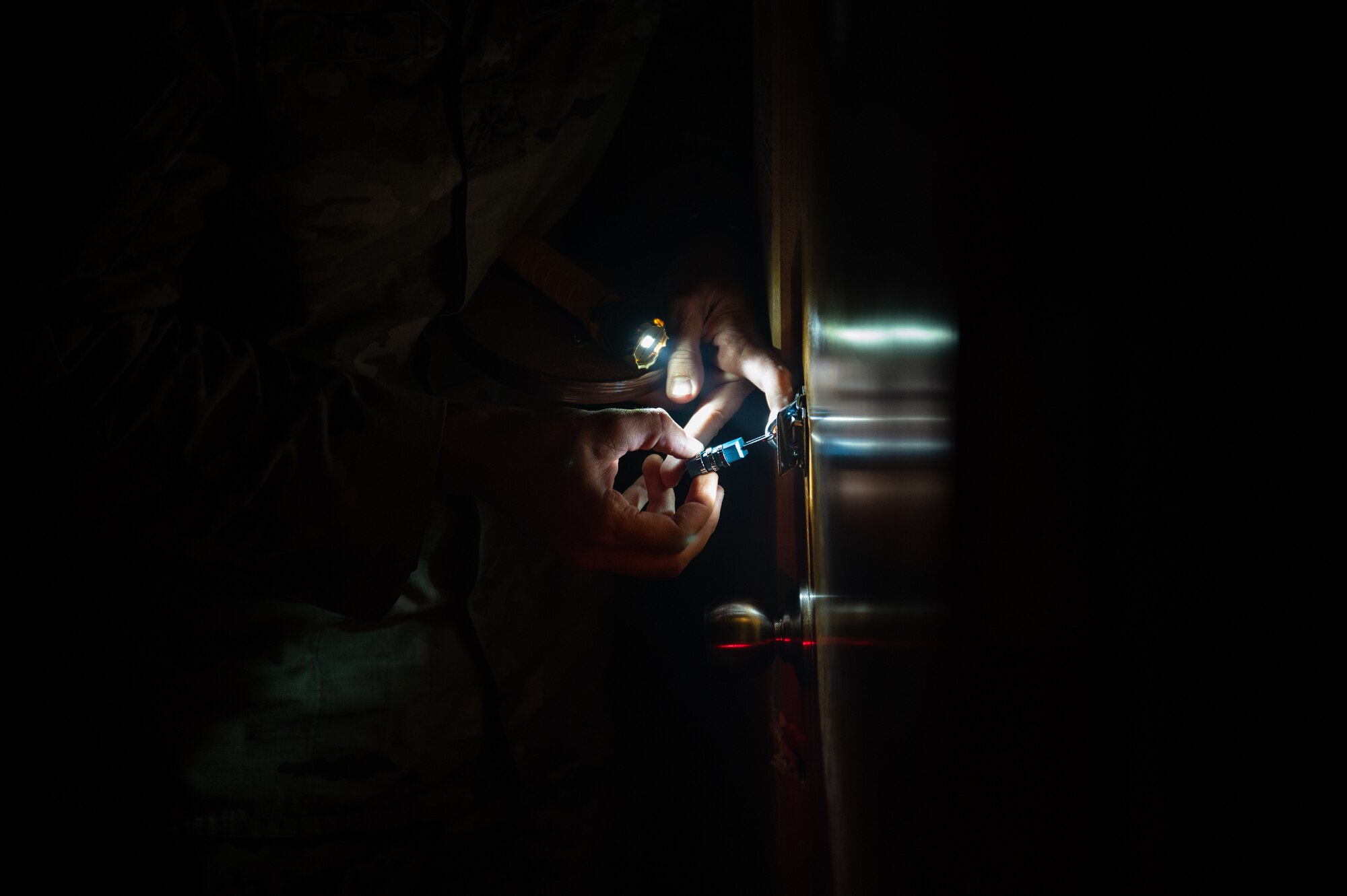 U.S. Air Force Maj. Jacob S. Flatz, 379th Expeditionary Civil Engineer Squadron deputy commander, unlocks a padlocked door in simulated low visibility conditions Oct. 12, 2022 at Al Udeid Air Base, Qatar. The escape room fire safety exercise helps to build upon fundamentals of fire safety such as communication, problem solving and planning. (U.S. Air Force photo by Staff Sgt. Dana Tourtellotte)