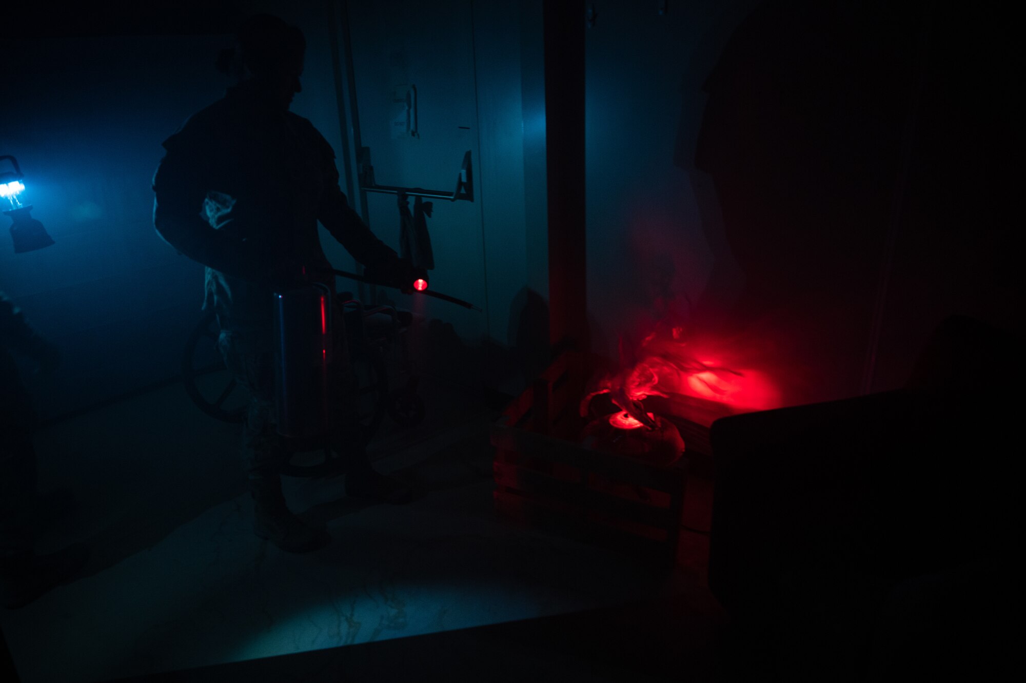 U.S. Air Force Lt. Col. Korinne K. Takeyama, 379th Expeditionary Civil Engineer Squadron commander, extinguishes the simulated flames in a fire escape room exercise for fire safety awareness Oct. 12, 2022 at Al Udeid Air Base, Qatar. The Airmen had to work together to find clues, unlock padlocks and perform a rescue as part of an exercise to impress upon people the importance and challenge of fire safety awareness.